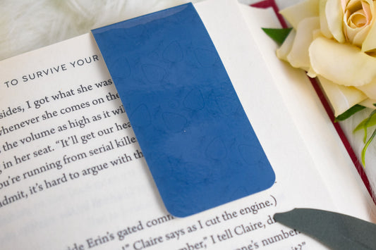 Blue bookmark on a book with a rose in the background