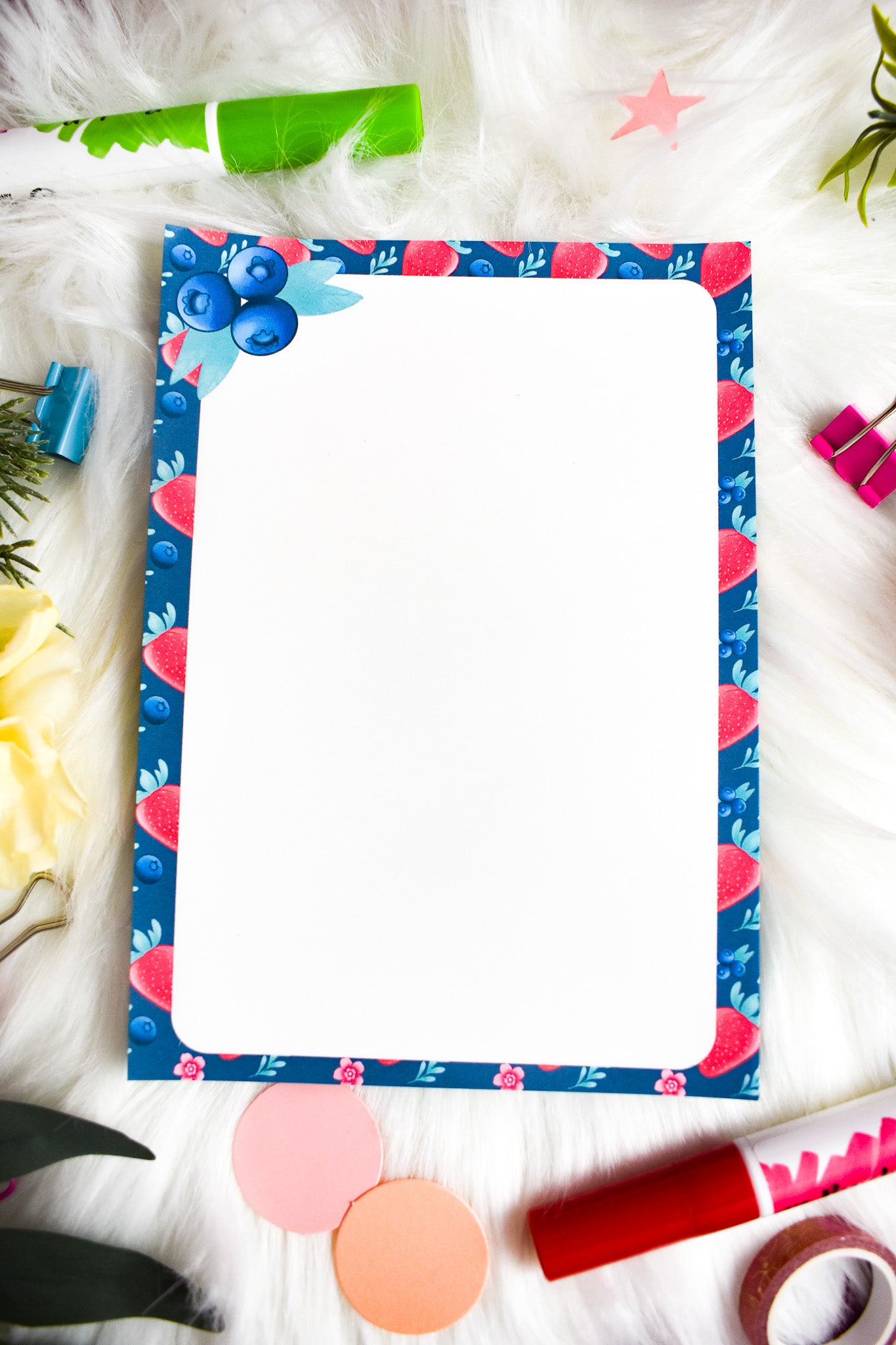 Notepad with decorative border on a white surface with flowers and clips.