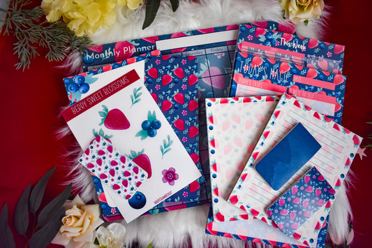 Collection of stationery items including planners, stickers, and bookmarks on a red surface with flowers