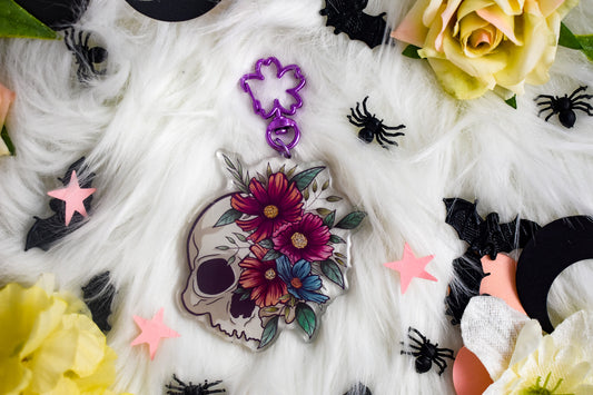 Decorative skull with floral design surrounded by colorful stars and spider decorations on a white surface.