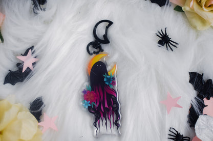 Decorative keychain with a stylized ghost design on a white fabric background.