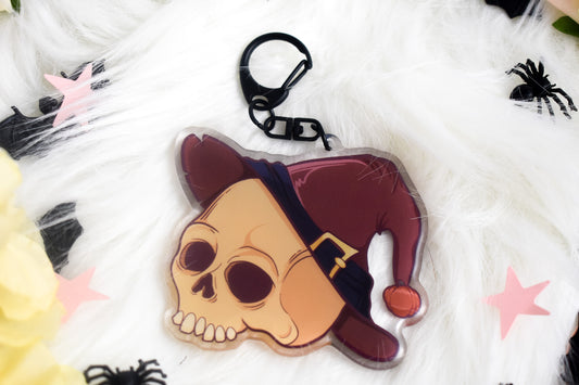 Skull-shaped keychain with a hat on a white background with spider decorations