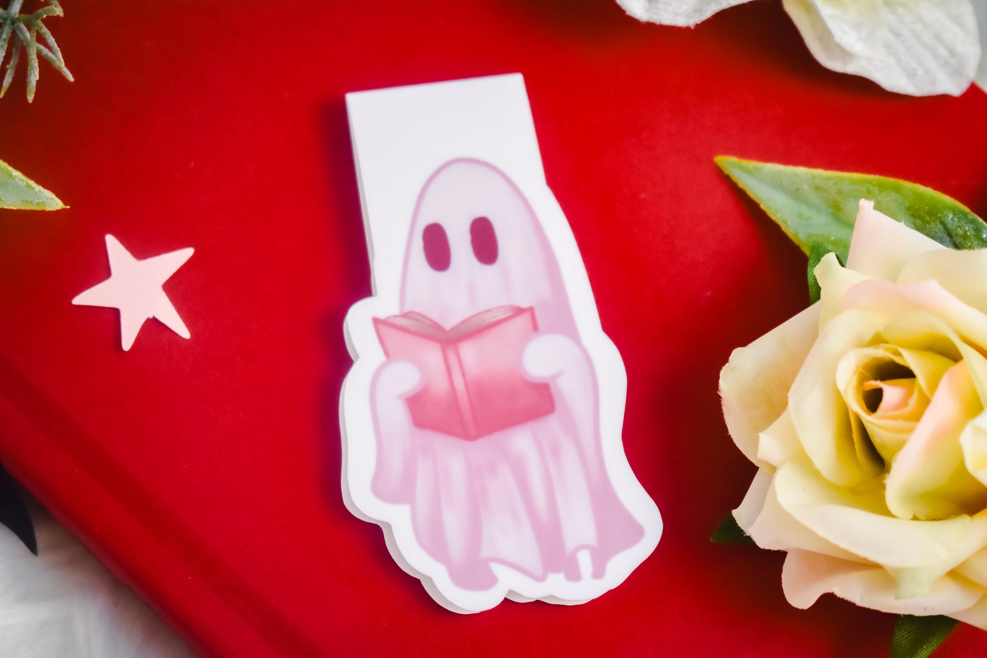 Ghost holding a book on an open book with yellow roses in the background