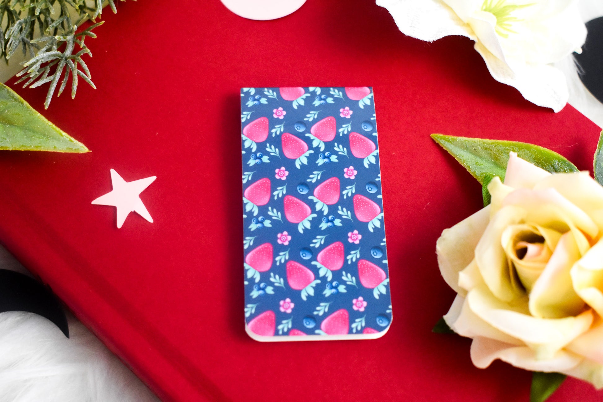Open book with a blue strawberry patterned bookmark surrounded by yellow flowers