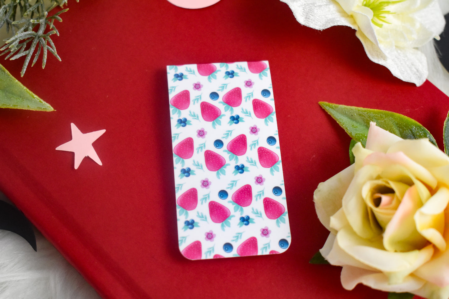 White bookmark with strawberry pattern on a book with a rose in the background