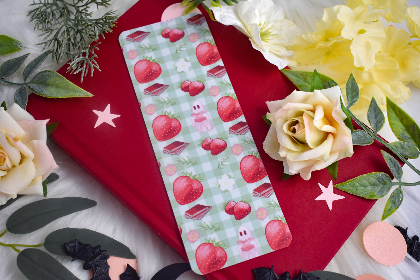 Bookmark with strawberry design on a red book with flowers and leaves.