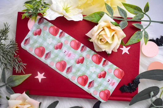 Bookmark with strawberry design on a red book with flowers and leaves.