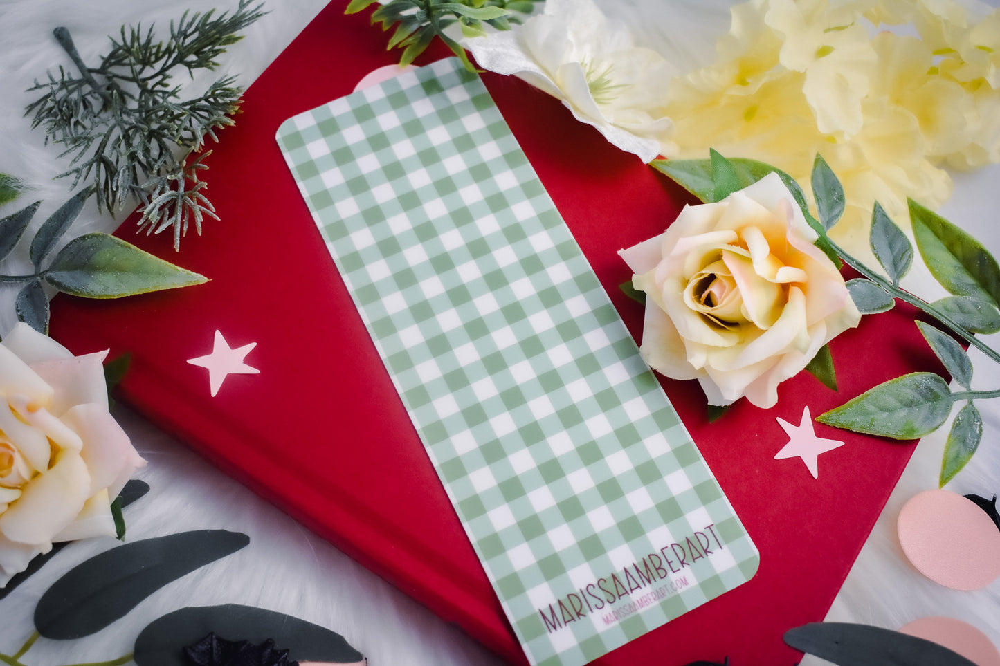 Bookmark with gingham design on a red book with flowers and leaves.