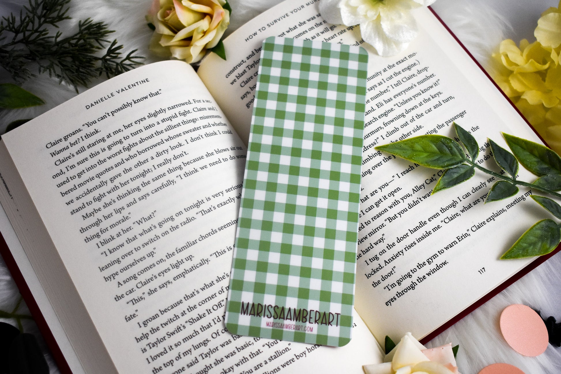 Green and white checkered bookmark on an open book with flowers around