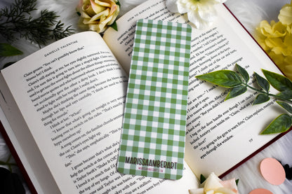 Green and white checkered bookmark on an open book with flowers around