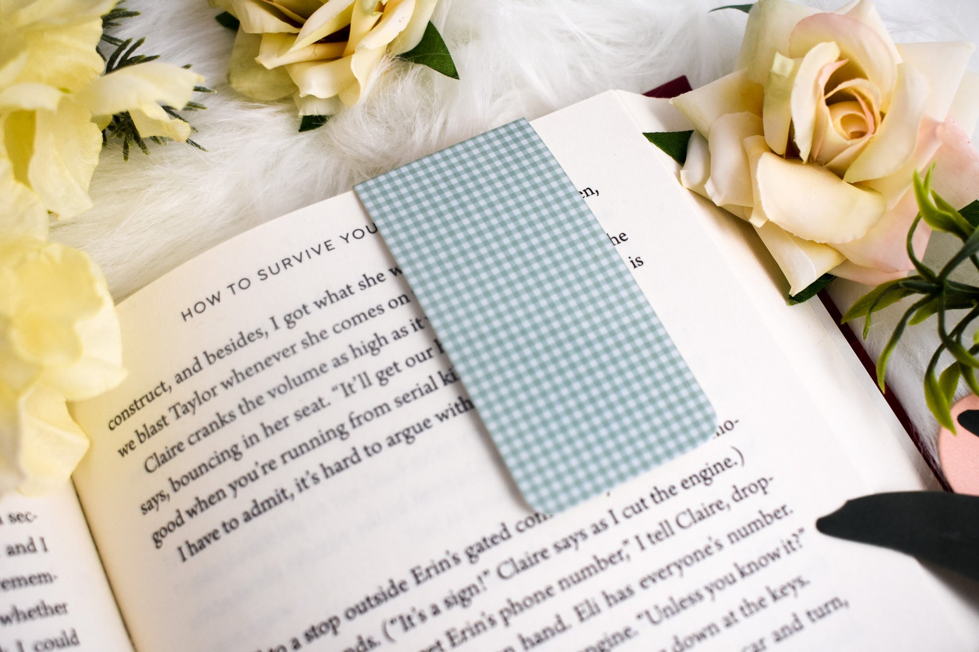 Open book with a green gingham bookmark surrounded by yellow flowers