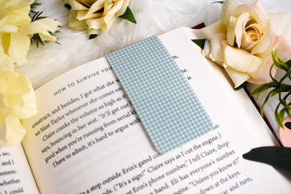 Open book with a green gingham bookmark surrounded by yellow flowers