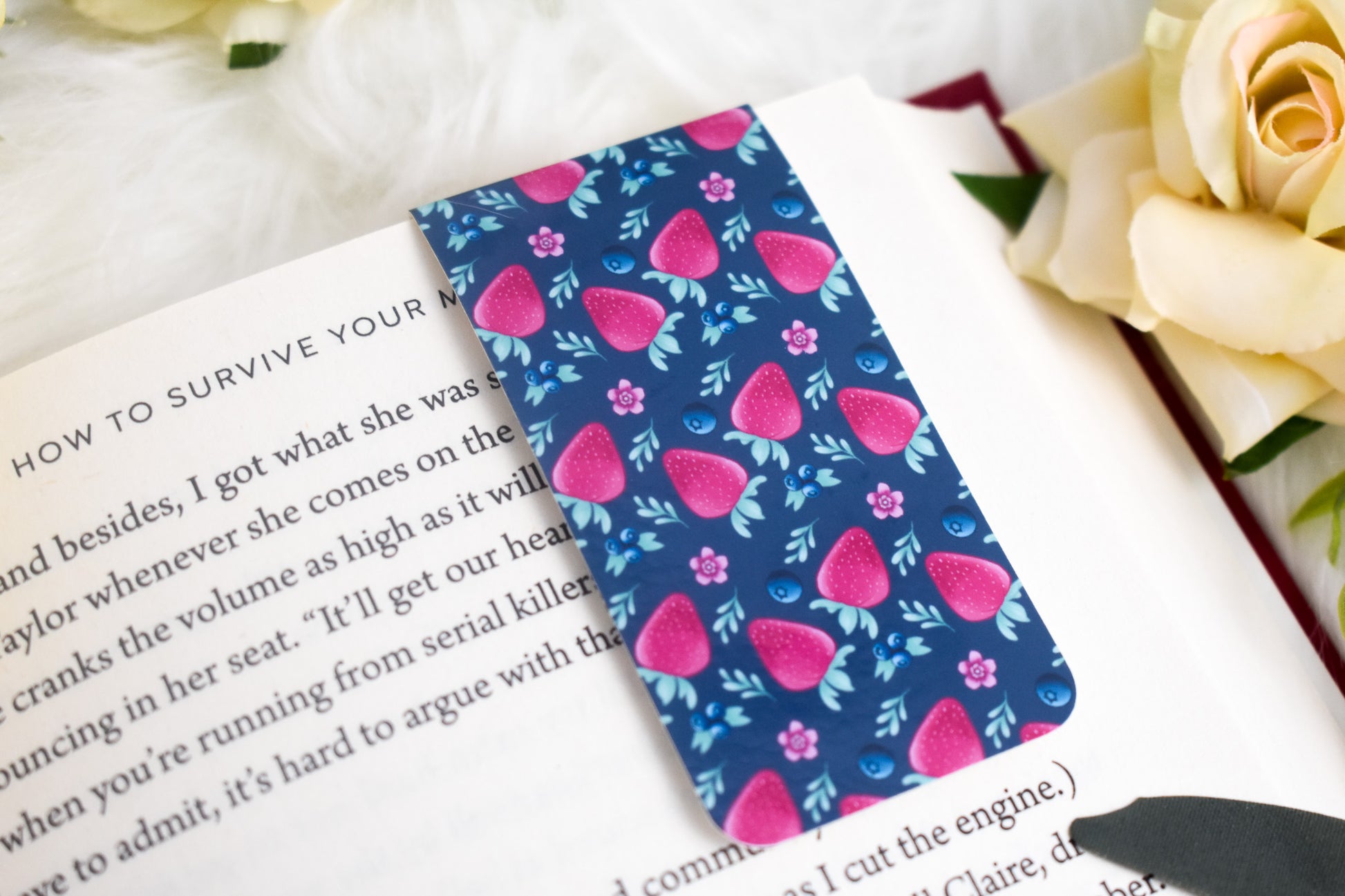 Open book with a blue strawberry patterned bookmark surrounded by yellow flowers
