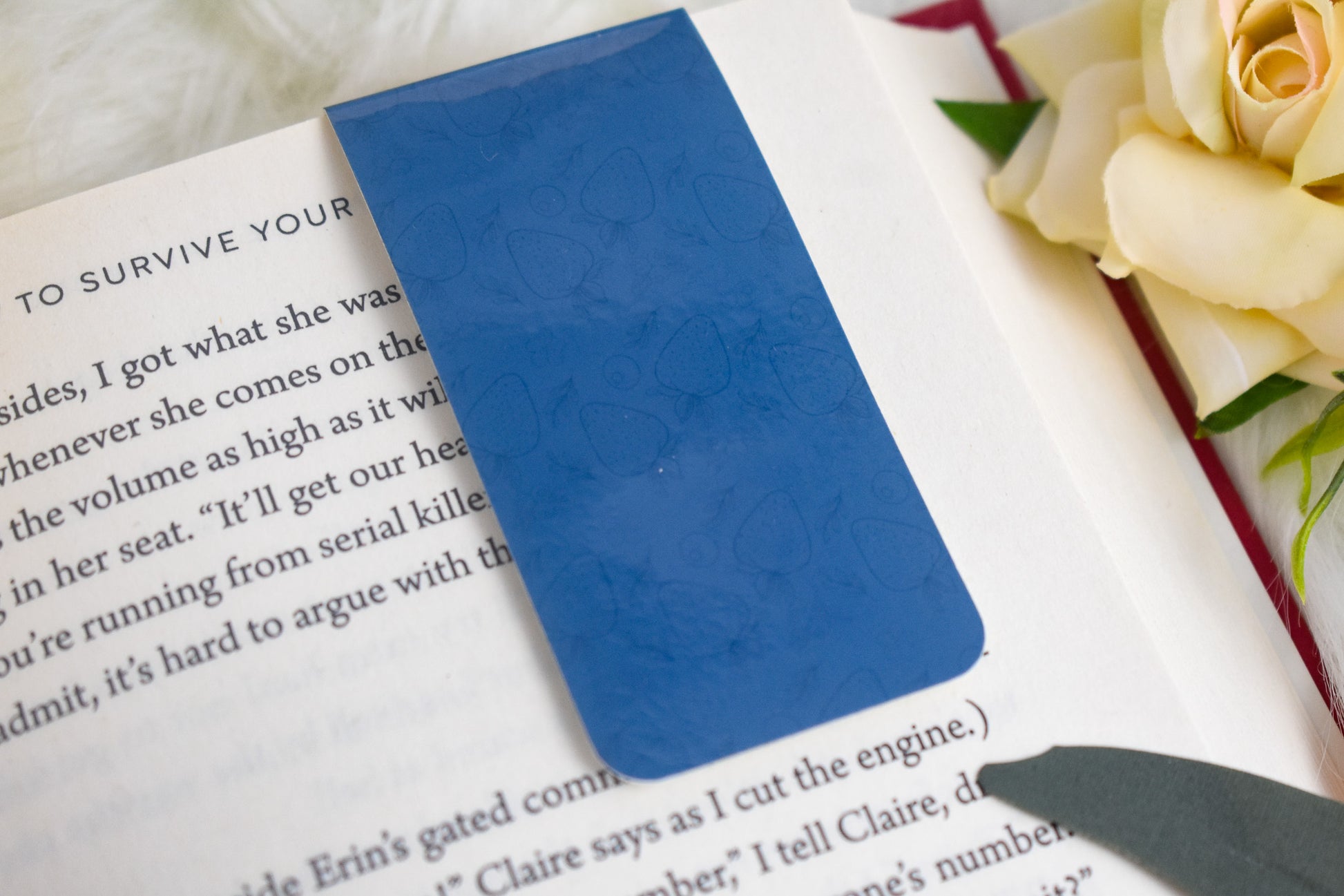 Blue bookmark on a book with a rose in the background