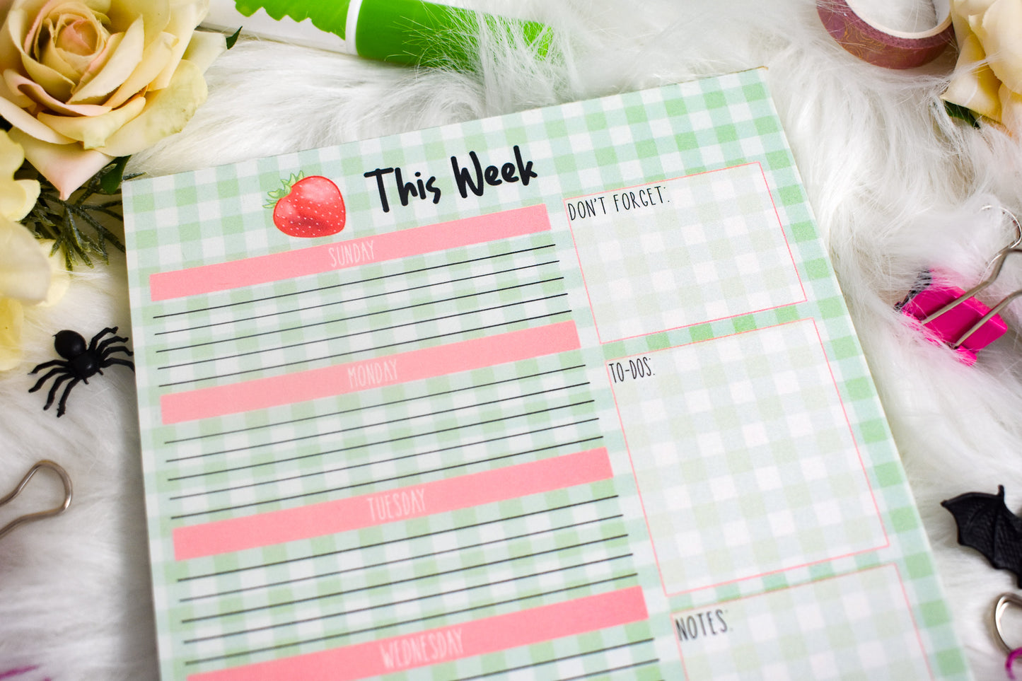 Weekly planner sheet with decorative elements on a white surface with flowers and stationery items.