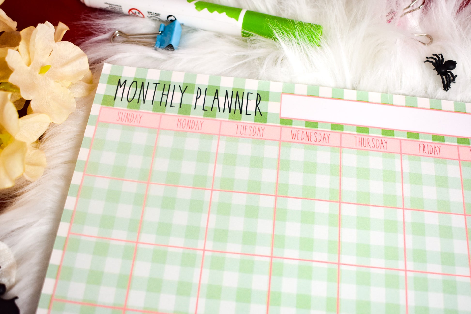 Monthly planner with a green and white checkered pattern on a surface with decorative items.