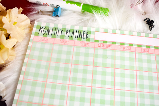 Monthly planner with a green and white checkered pattern on a surface with decorative items.