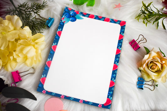 Notepad with decorative border on a white surface with flowers and clips.