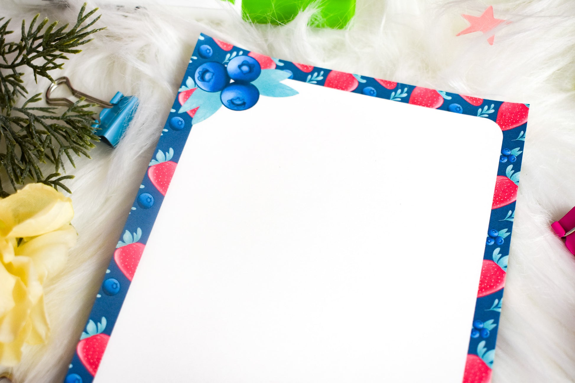 Notepad with decorative border on a white surface with flowers and clips.