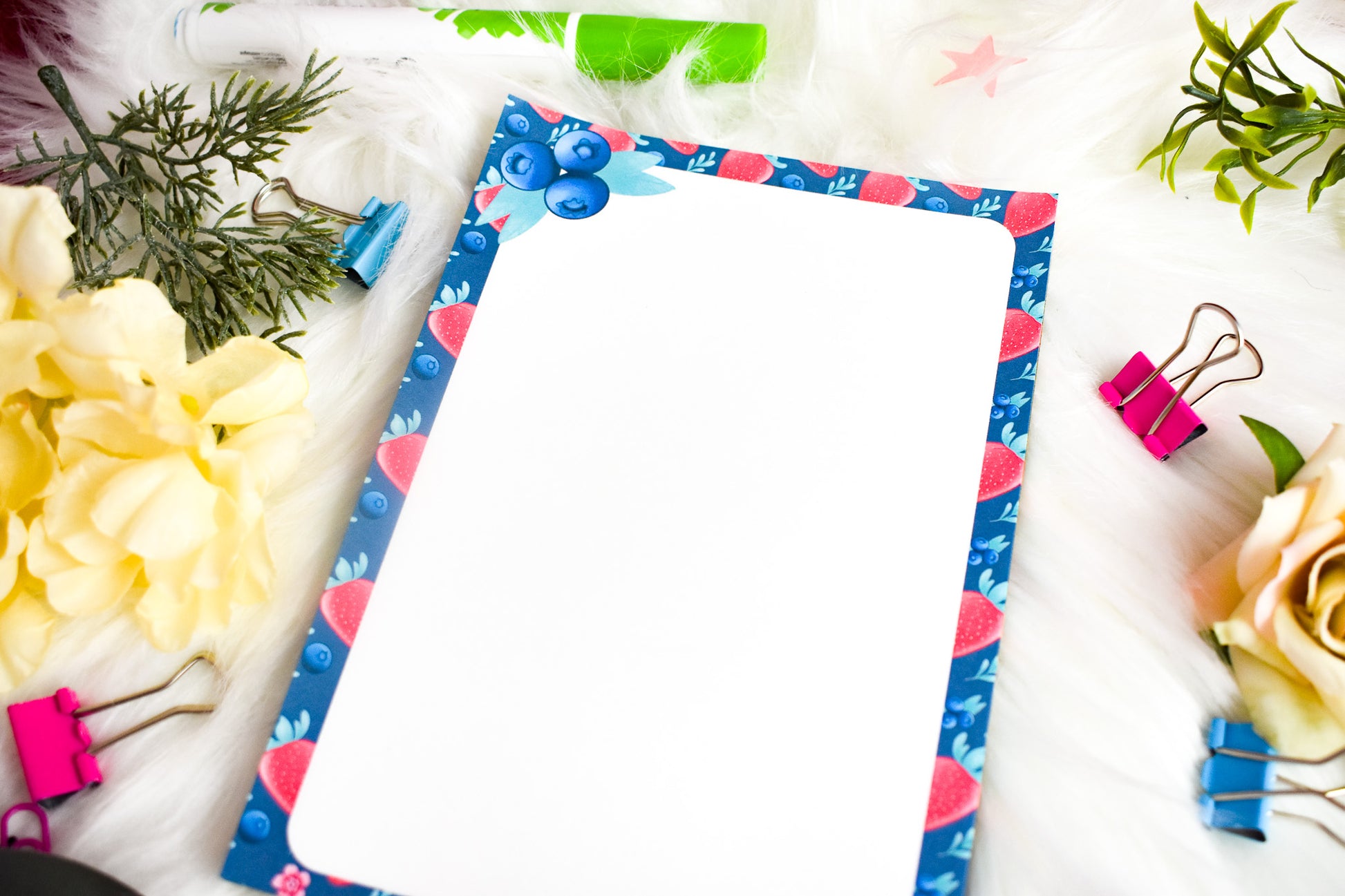 Notepad with decorative border on a white surface with flowers and clips.