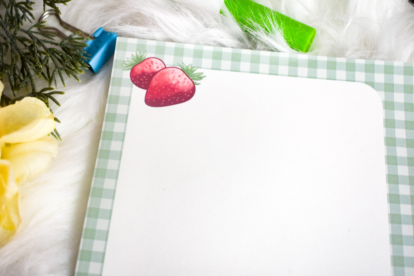 Notepad with a ghost illustration on a desk with flowers and stationery items
