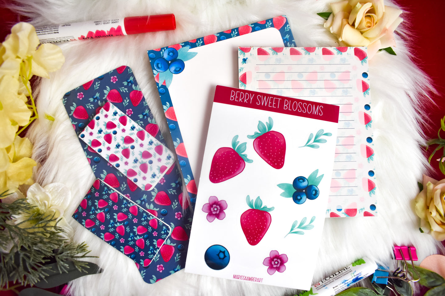 a lined notepad, a blank notepad, sticker sheet, 2 magnetic bookmarks and traditional bookmark with strawberry designs on a white background