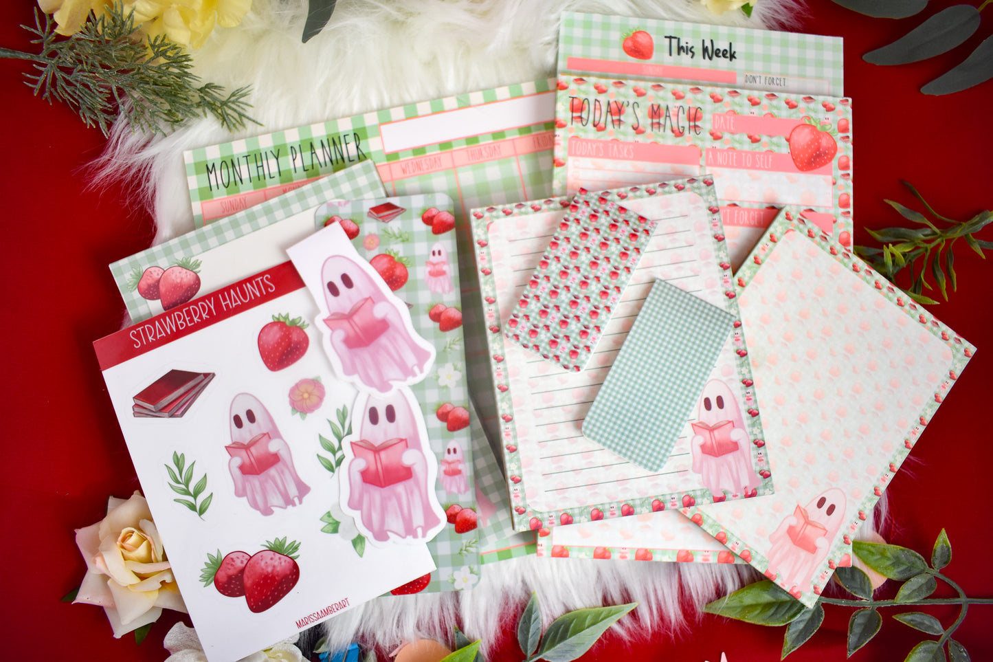 Stationery items including notepads, stickers, bookmarks, and planners on a red background with decorative elements.
