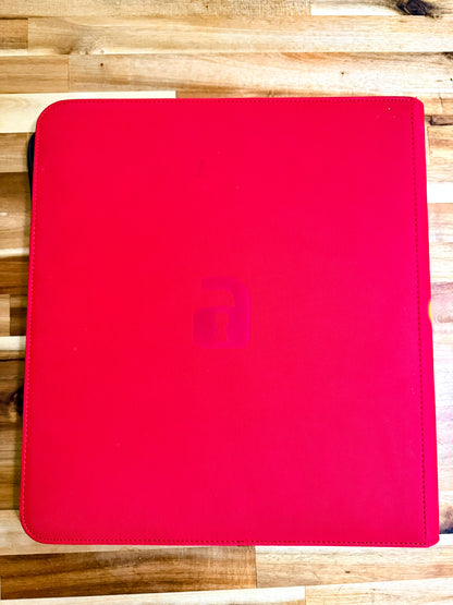 A bright red tablet sleeve or folio case with a subtle embossed lowercase 'lock' logo in the center, shown on a light wood plank surface.