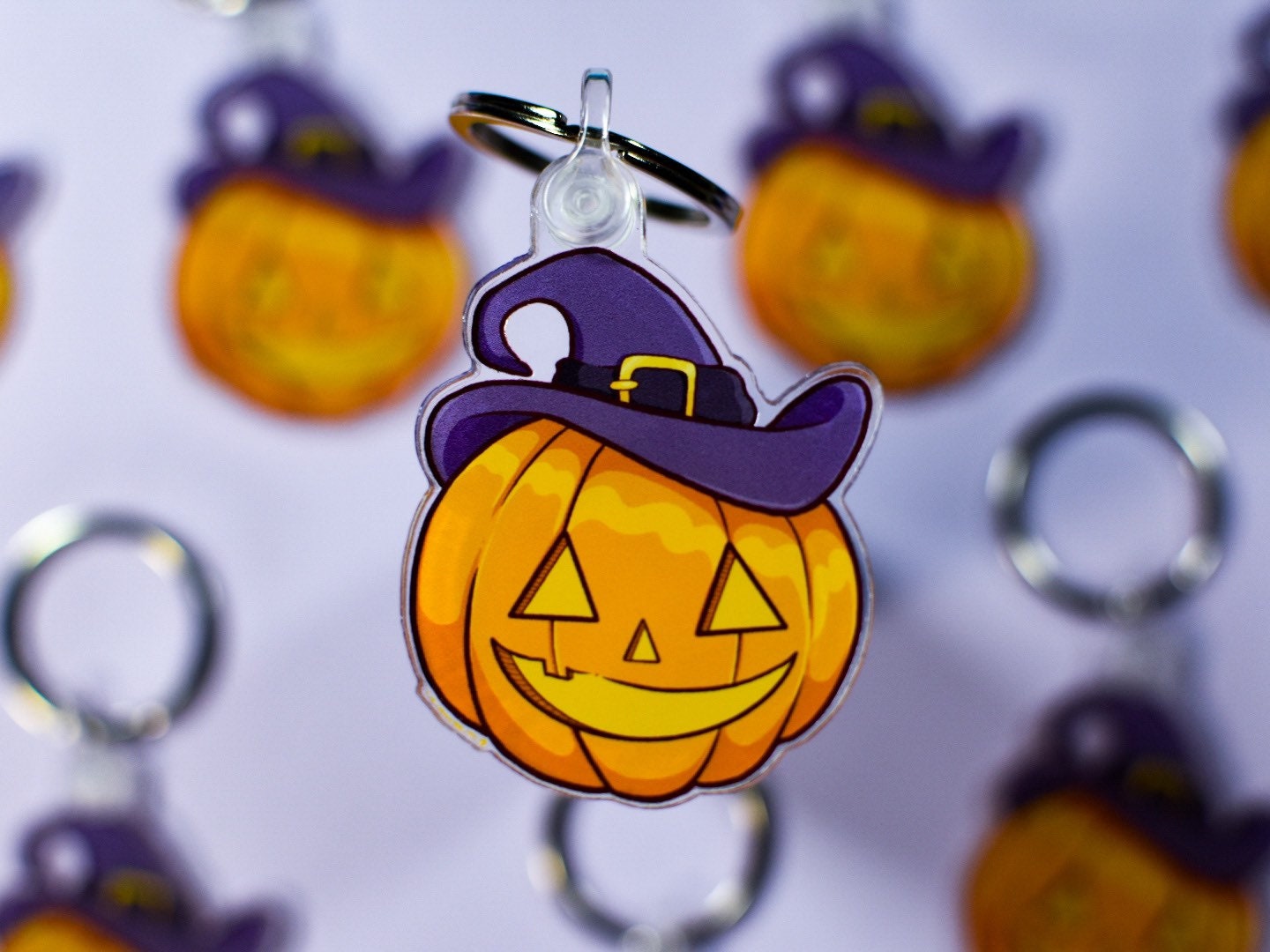 Halloween-themed keychain with pumpkin design and purple witch hat on a white background.