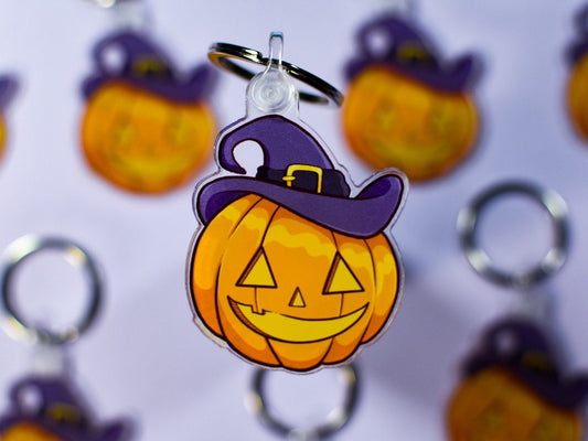 Halloween-themed keychain with pumpkin design and purple witch hat on a white background.